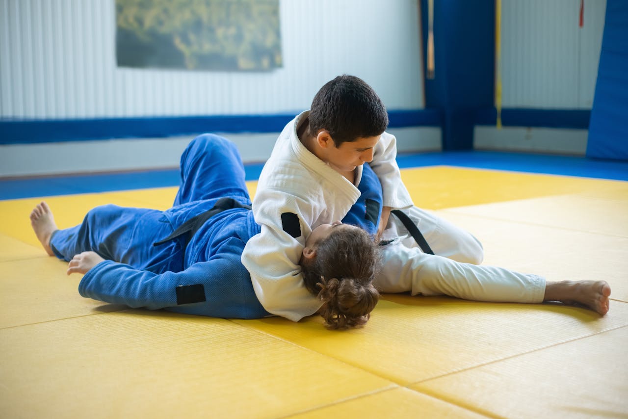 Two judo practitioners engage in grappling on a tatami mat during training.